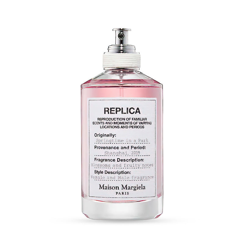Maison Margiela Replica fragrance bottle, labeled "Springtime in a Park," with a pink liquid and a silver spray nozzle, described as a unisex scent with blossoms and fruity notes.